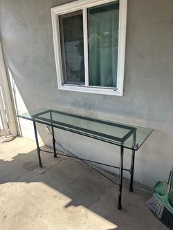 glass-top console table with an ornate black metal frame.