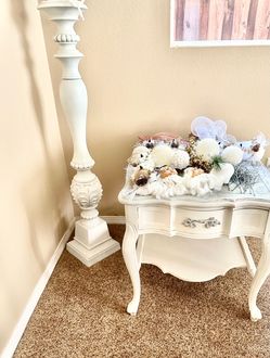 a vintage, French Provincial-style white accent table with curved cabriole legs and an ornate metal drawer pull.