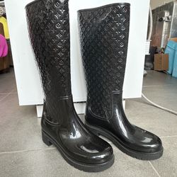 This is a pair of Louis Vuitton 'Splash' high rain boots in black rubber with an embossed monogram print