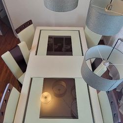 Six elegant faux leather dining chairs are included with a high-gloss and chrome metal rectangle dining table set