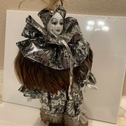 Vintage porcelain silver Pierrot doll with brown feathers. Includes wood stand.