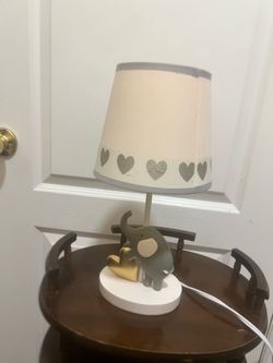 Charming elephant-themed nursery lamp with a matching shade. This Bedtime Originals Eloise model has a gray elephant and gold heart base with a white 