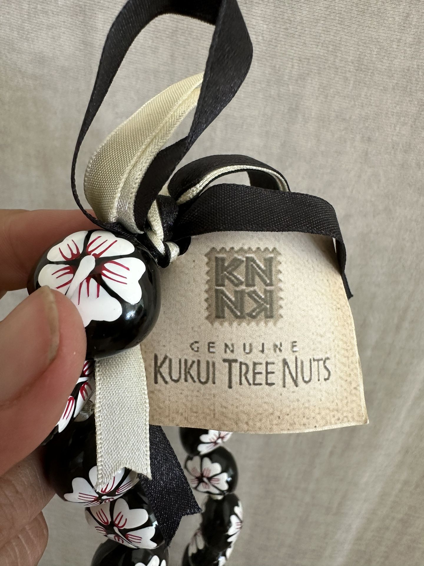 Painted Kukui Nut Choker Lei Necklace, 19 inches. Kukui Nuts are hand painted and laced on a ribbon that ties in the back. Hibisucs flowers are white
