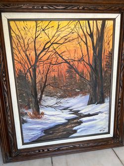 original winter landscape oil painting featuring a winding stream through snow-covered woods under an orange and yellow sunset sky, framed in an ornat