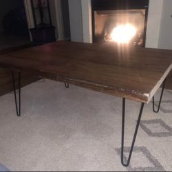 Rustic industrial-style coffee table featuring a solid wooden top and black metal hairpin legs