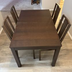 Dark brown extendable dining table with four chairs