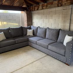 8x10 “L” sectional new in plastic gray fabric with silver nail heads