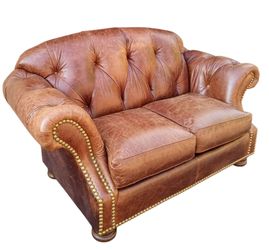 Elevate your living space with the timeless  of this Thomasville Chesterfield leather sofa and matching ottoman.