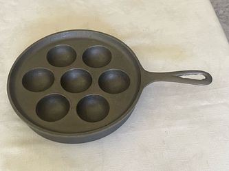 Vintage cast iron pan with seven hemispherical molds for making aebleskiver.