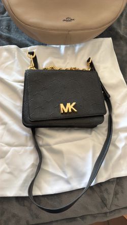 This black textured leather Michael Kors Mott crossbody bag features a distinctive gold-toned chain handle and prominent logo hardware.