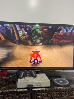Selling a like-new PlayStation 1 with cables and the game Crash Bandicoot.