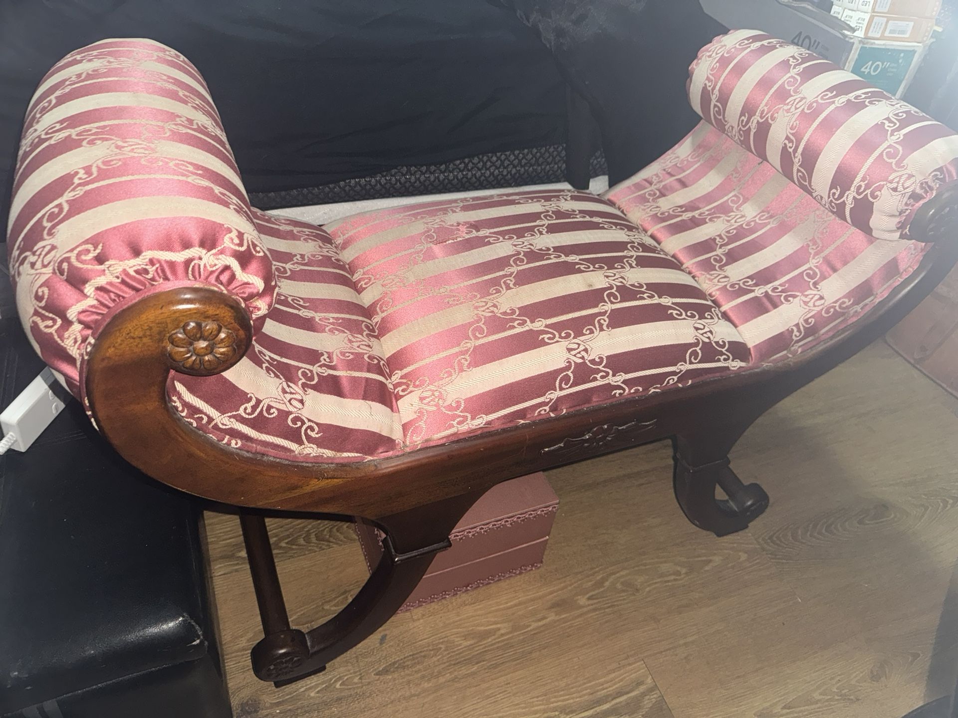 This is an antique or vintage chaise lounge with a pink and white striped damask upholstery