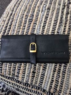 Black leather travel jewelry roll with a polished gold-tone buckle. Sleek, organized interior design for daily use. Timeless black leather complements