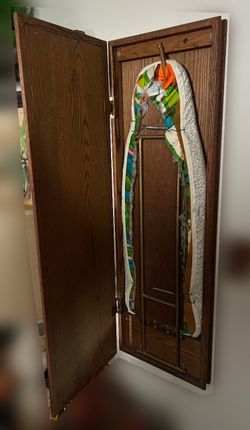 wall-mounted wooden cabinet containing a fold-down ironing board