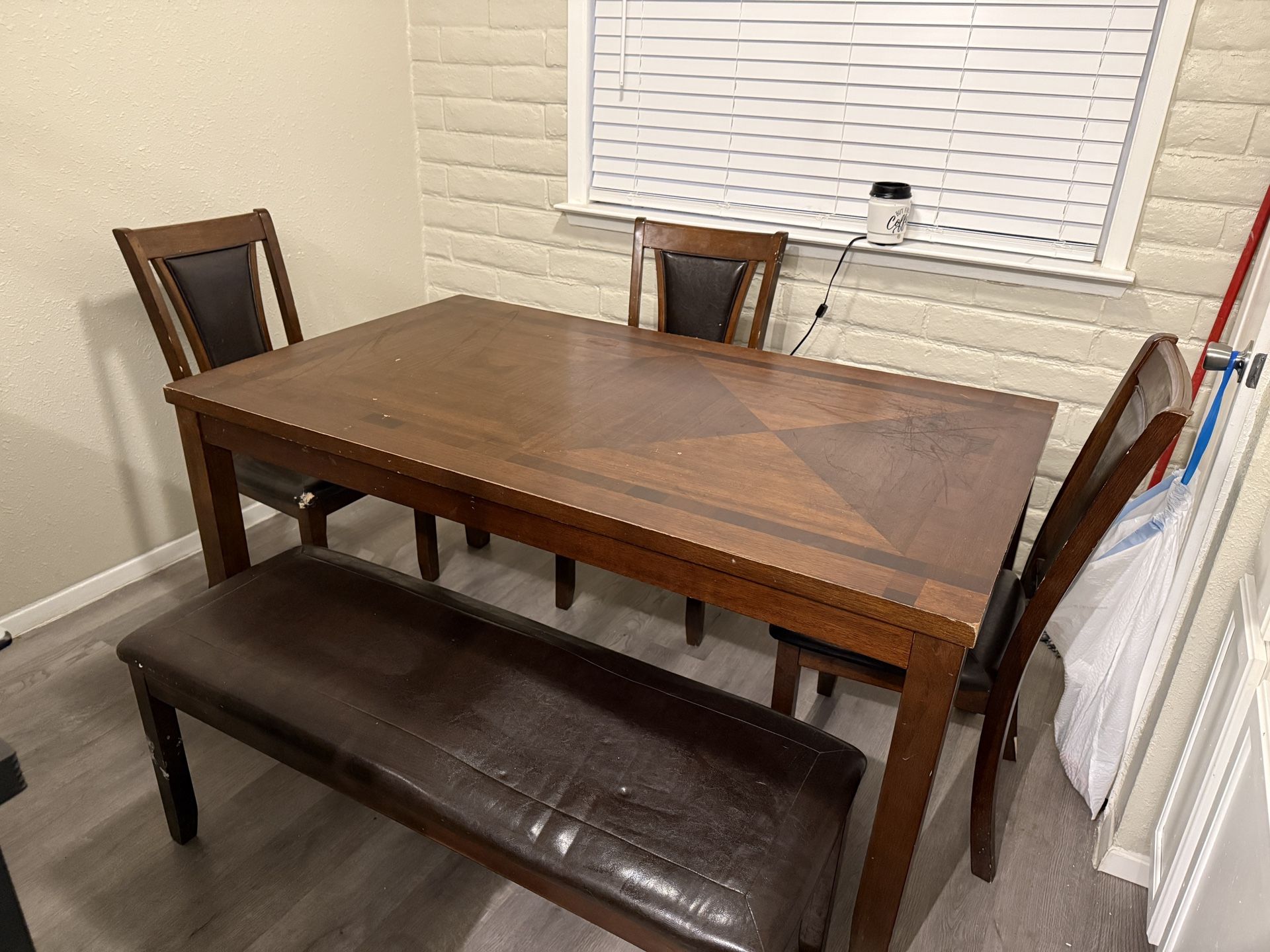 Table with 3 chairs and a large bench.