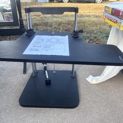 Black adjustable stand up desk table with clamp mechanism.
