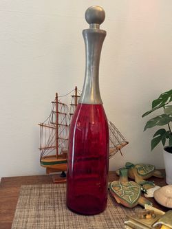 Decorative glass bottle with red base and metallic neck.