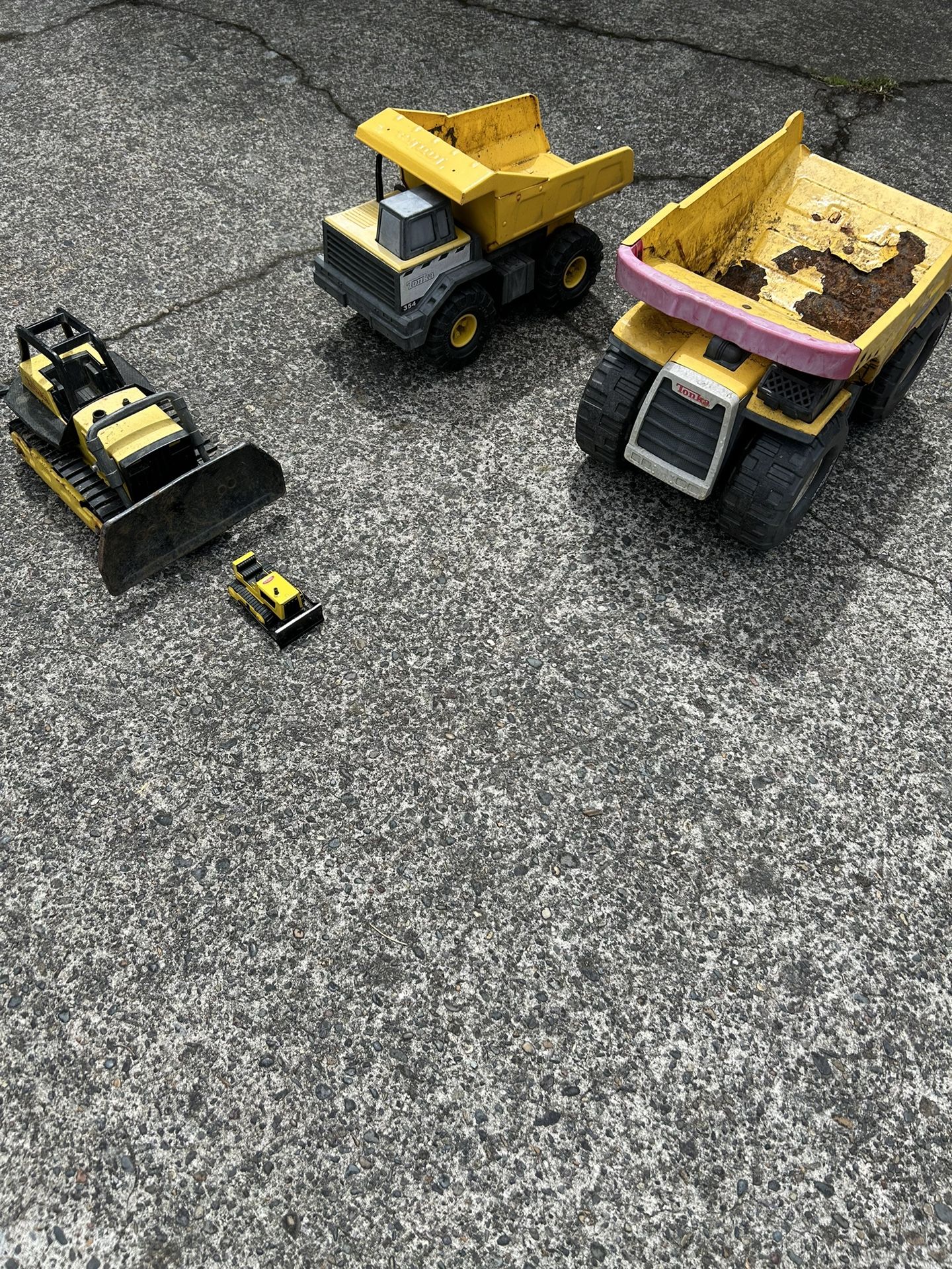 4 Tonka toys in decent shape. The larger of the dump trucks has some peeling paint. The bulldozer is a little dirty, but the tracks still work. The s