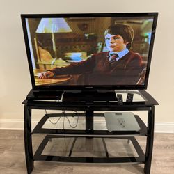 NICE AND MODERN TV STAND WITH THREE GLASS SHELVES. IT MEASURES 45 BY 27 BY 15  INCHES. $60.00  OR BEST OFFER.