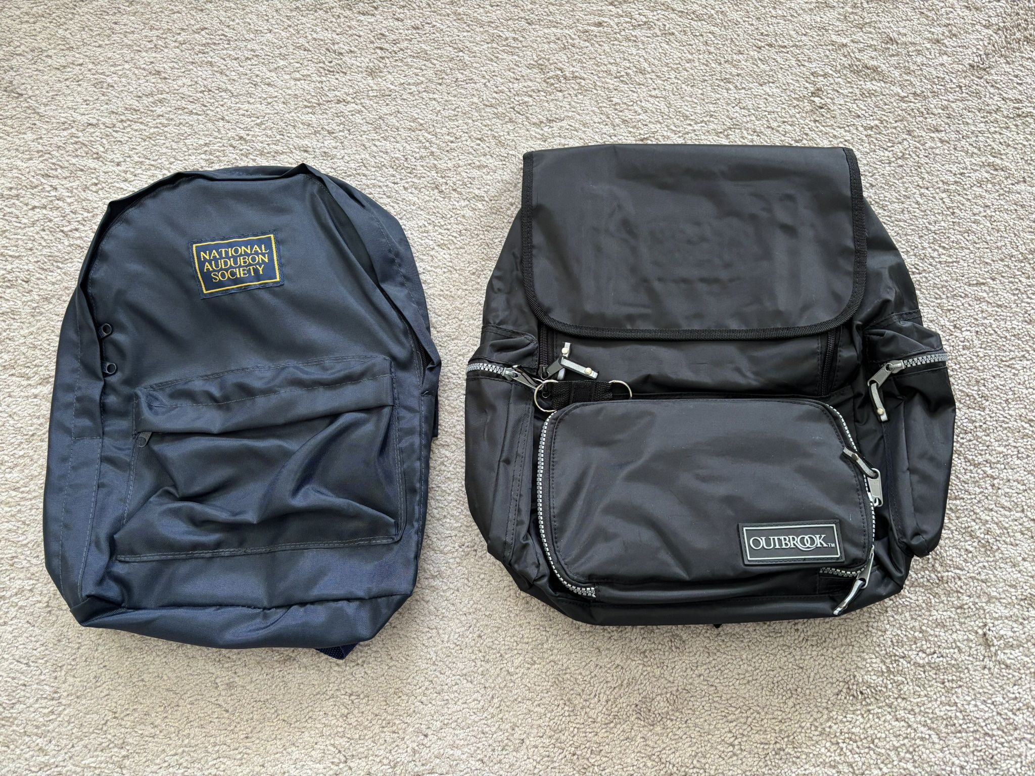 Backpacks, lot of 2, new. 1 premium Outbrook heavy duty vinyl black 18” x 16” with 6 zippered compartments. 1 lightweight National Audubon Society vi