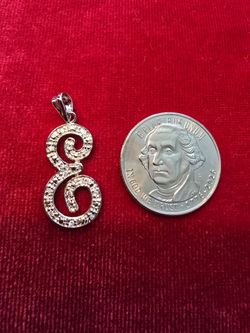 Delicate sterling silver initial pendant in a scripted "E" design. Features a polished, textured finish that catches the light. Easy to wear as a pers