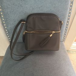 Black shoulder purse with front zipper pocket and tassel