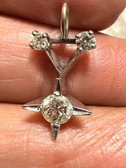 platinum pendant featuring a prominent four-pointed star setting with a round center diamond and two smaller accent diamonds at