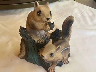 chipmunks/squirrels perched on a tree stump with an acorn