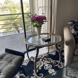 Decorative side table . Metal frame has light bronze finish. Glass top has scalloped edge .