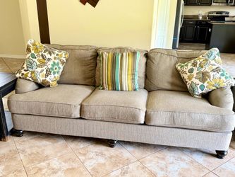 Ashley Furniture sofa with turned legs and patterned toss pillows.