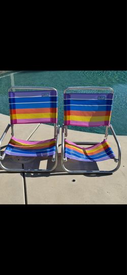 Rio Brands folding low-profile beach chairs featuring a vibrant rainbow-striped polyester fabric.