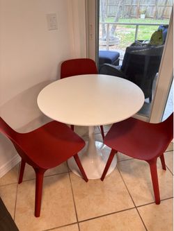 White pedestal table with three chairs