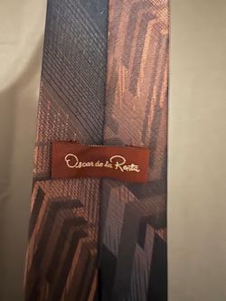 Oscar de la Renta necktie featuring a distinct brown, bronze, and black geometric Art Deco chevron pattern.