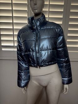 Cropped puffer with a metallic sheen. Full zip front and high neck for coverage. Lightweight puff insulation for warmth. Sleek,modern styling. Drawstr
