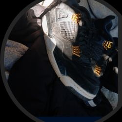 Nike Air Jordan 4 Retro "Royalty" sneakers, featuring a black suede upper with metallic gold accents. 