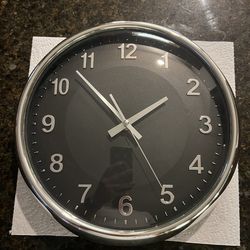 Modern Chrome-Rimmed Wall Clock with a black face and raised (3D) silver Arabic numerals.