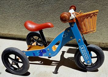 KRIDDO 2-in-1 wooden tricycle features a distinctive blue frame with a dinosaur graphic and a small wicker basket attached to the handlebars.This vers