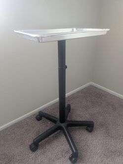 aluminum rolling salon and tattoo service tray cart with a black  wheeled base.