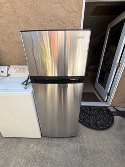 Haier stainless refrigerator with top freezer. It works and has dents on the doors