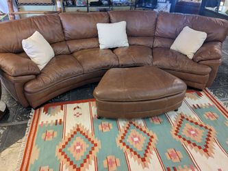 Rounded brown leather couch with storage ottoman on wheels