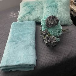 Two turquoise pillows, a turquoise blanket and the gray and turquoise flowers