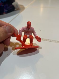 red plastic hockey goalie action figure, likely from a set like the Kaskey Kids Hockey Guys or similar toy/table hockey lines featuring a Detroit Red