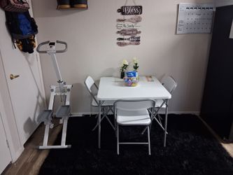 Plastic white folding table, chairs and rug.