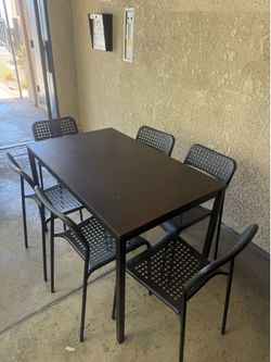 Black dining table with six stackable chairs