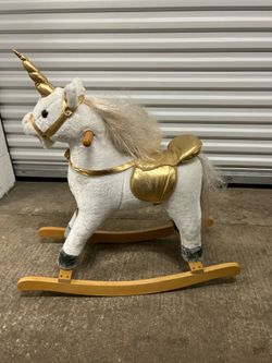 a plush unicorn rocking horse in white with gold detailing and a twisted horn with sounds