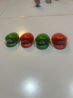 4 official Super Mario Bros. Wonder x 7-Eleven Japan Collaboration bottle caps shaped like Mario and Luigi's signature hats (red "M" and green "L" cap