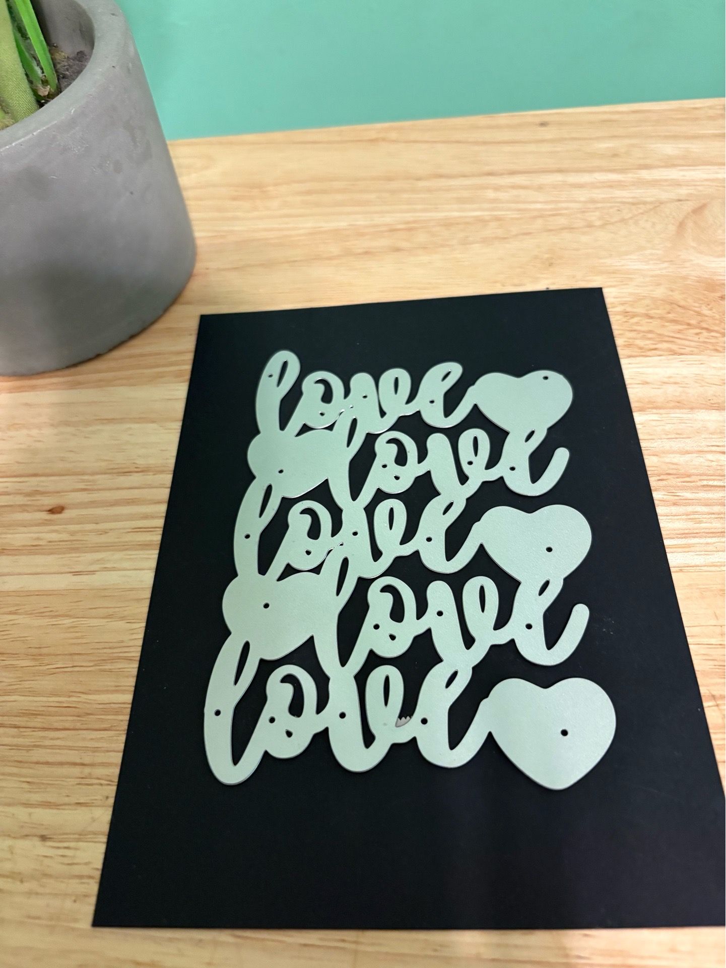 Decorative die-cut sheet with repeated "love" script and heart shapes. Lightweight craft piece. Great for cardmaking and scrapbooking.