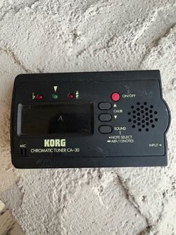 black Korg CA-30 Chromatic Tuner featuring a digital LCD screen, LED tuning indicators, and a built-in speaker