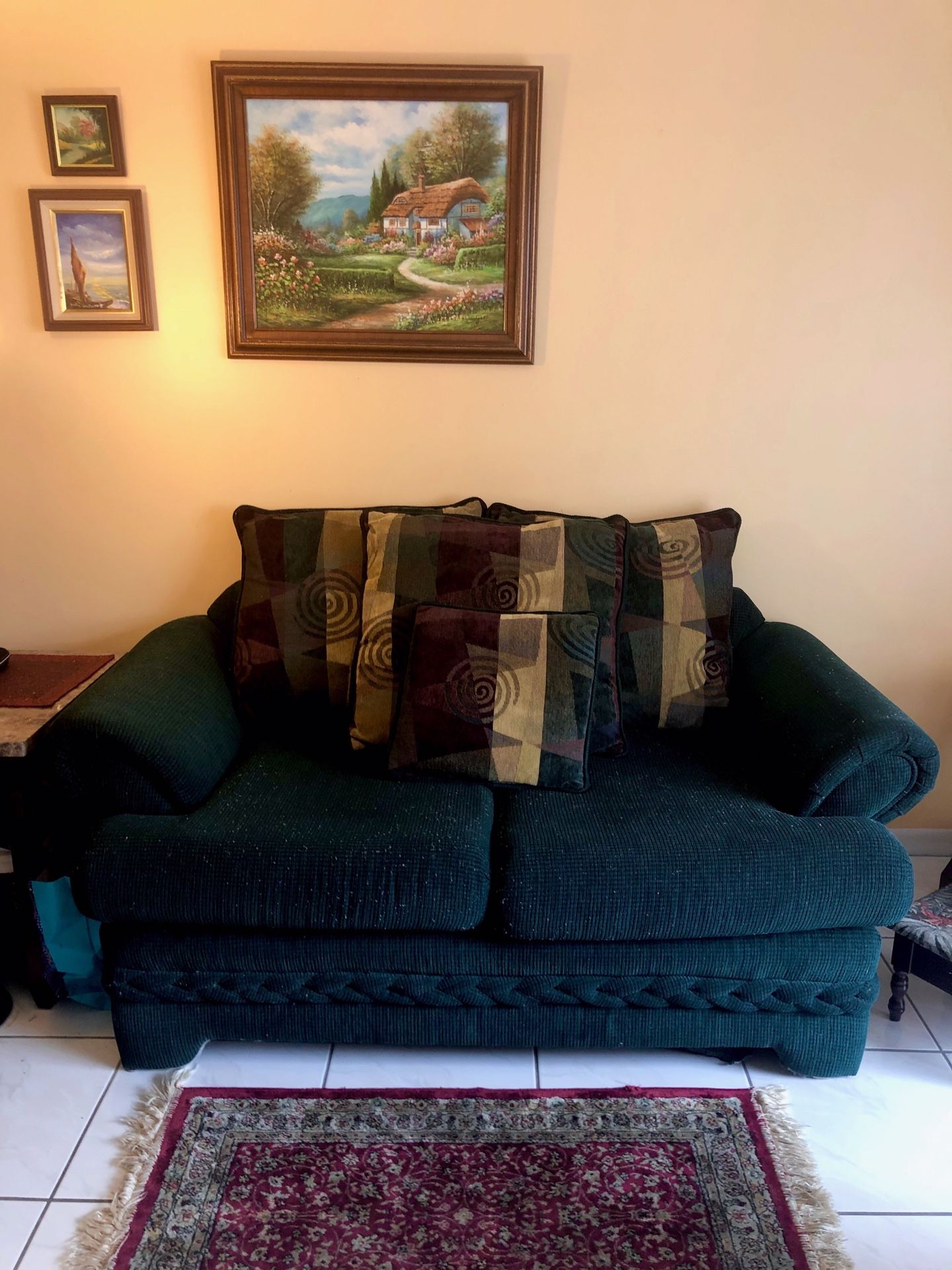 green love seat with large printed pillows