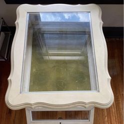 Cream Colored Wooden Table With Glass Top And Opening Cupboard
